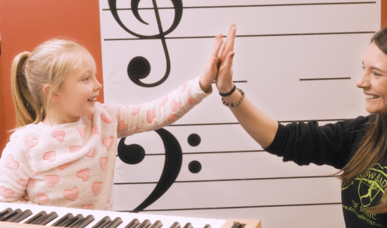 Student and teacher giving high five in piano lesson